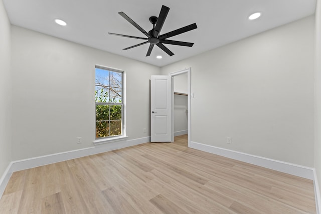 unfurnished bedroom featuring light wood-type flooring, a closet, a spacious closet, and ceiling fan