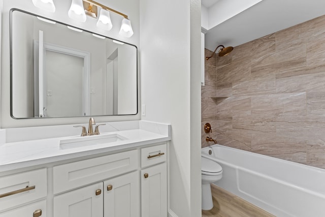 full bathroom with hardwood / wood-style floors, tiled shower / bath combo, toilet, and vanity