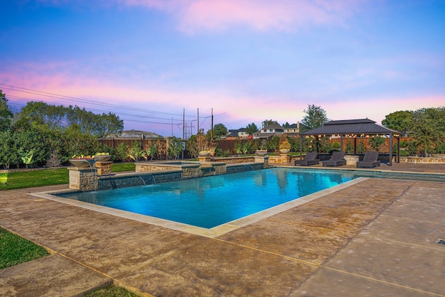 pool at dusk featuring a gazebo, a patio area, and pool water feature