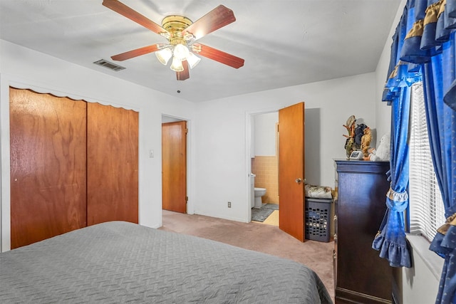 bedroom featuring ceiling fan, light carpet, a closet, and ensuite bath