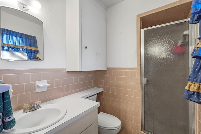 bathroom with tile walls, toilet, a shower with door, and vanity