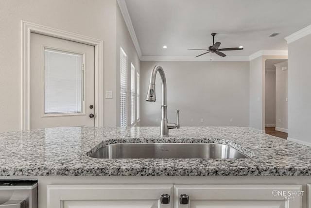 kitchen with ceiling fan, light stone countertops, sink, and ornamental molding