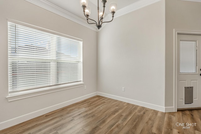 spare room featuring wood-type flooring, a chandelier, and ornamental molding