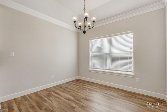 spare room featuring hardwood / wood-style flooring, an inviting chandelier, and ornamental molding