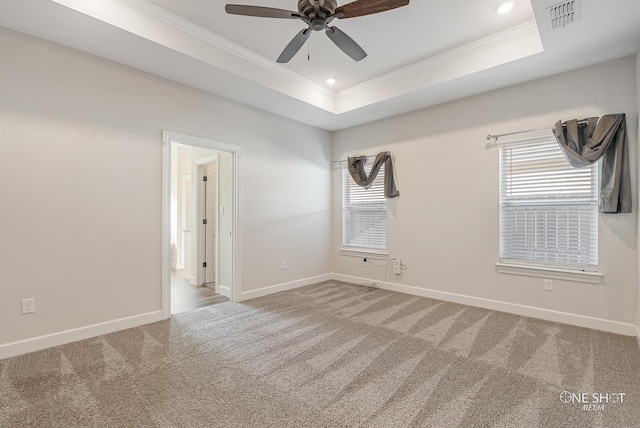 empty room with a tray ceiling, ceiling fan, and carpet flooring