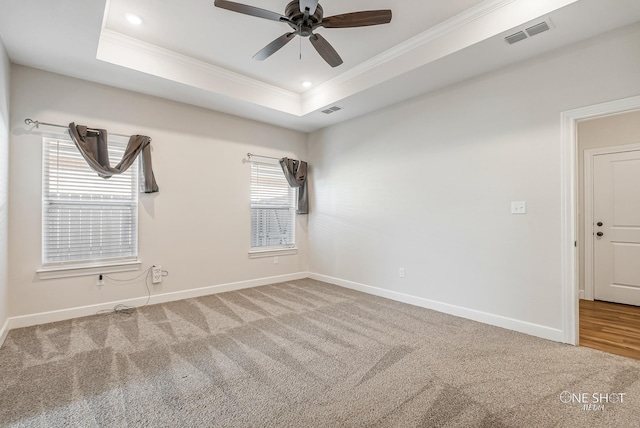 carpeted empty room featuring a tray ceiling, ceiling fan, and ornamental molding