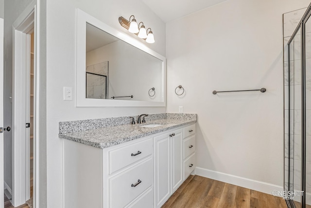 bathroom featuring wood-type flooring, a shower with door, and vanity