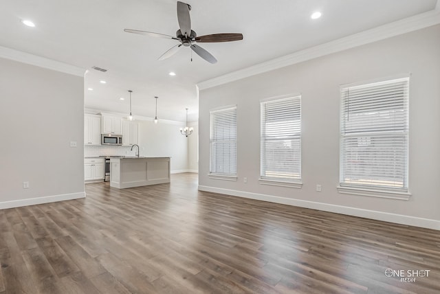 unfurnished living room with sink, crown molding, and dark wood-type flooring