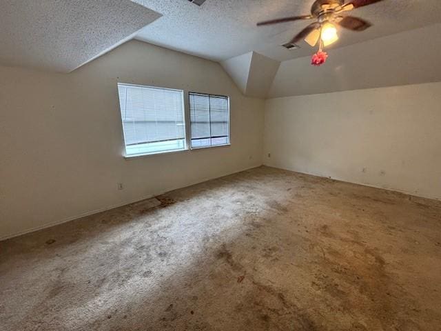 additional living space with vaulted ceiling, carpet floors, ceiling fan, and a textured ceiling