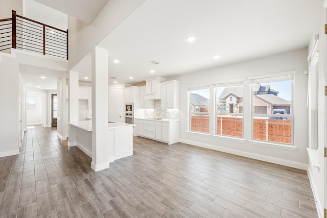 kitchen with tasteful backsplash, stainless steel appliances, light hardwood / wood-style flooring, and white cabinets