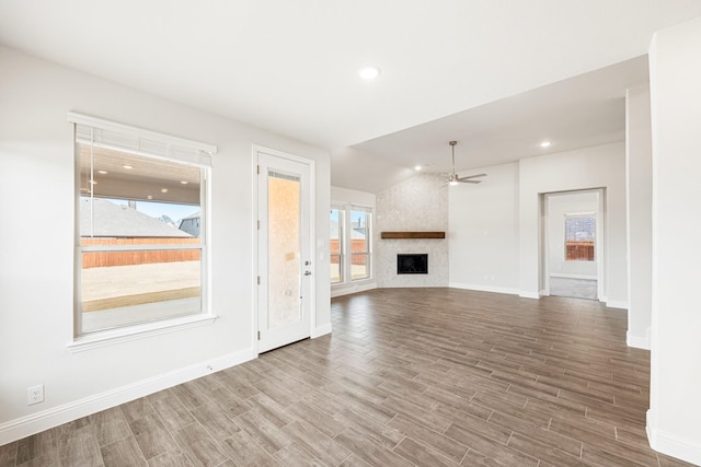 unfurnished living room featuring hardwood / wood-style flooring, a large fireplace, and a healthy amount of sunlight