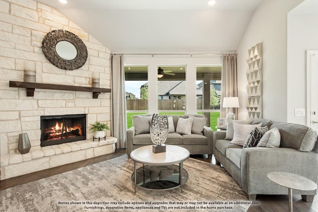 living room with hardwood / wood-style floors, ceiling fan, a stone fireplace, and vaulted ceiling