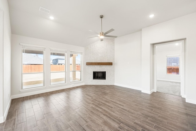 unfurnished living room with hardwood / wood-style flooring, vaulted ceiling, a large fireplace, and ceiling fan