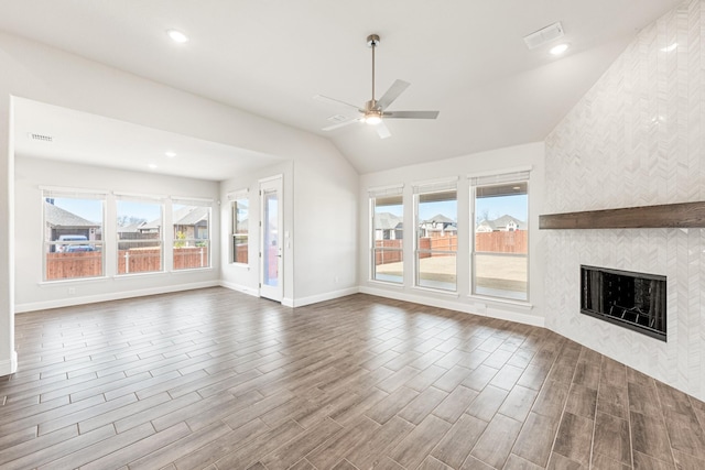 unfurnished living room featuring a tiled fireplace, wood-type flooring, lofted ceiling, and ceiling fan