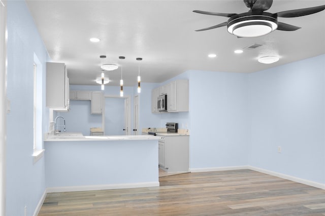 kitchen with white cabinets, pendant lighting, kitchen peninsula, and appliances with stainless steel finishes