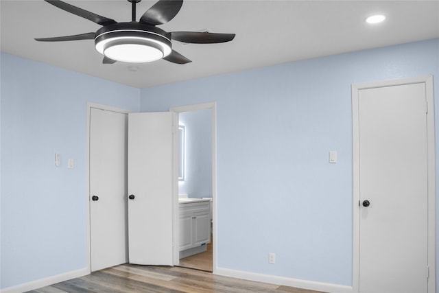 unfurnished bedroom featuring ensuite bathroom, light hardwood / wood-style flooring, and ceiling fan