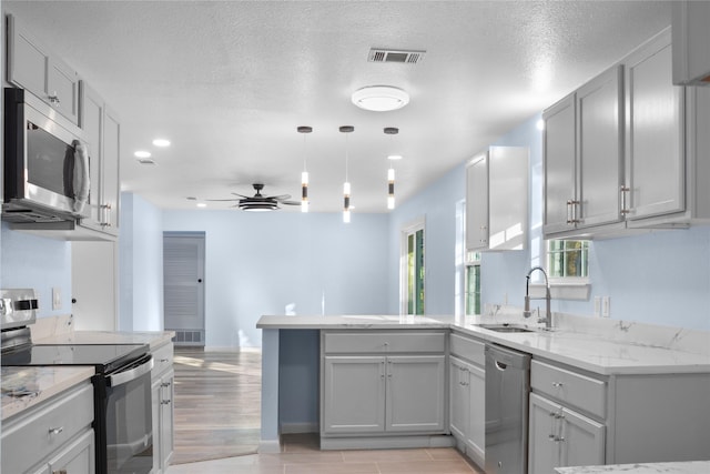 kitchen with kitchen peninsula, ceiling fan, gray cabinets, and stainless steel appliances