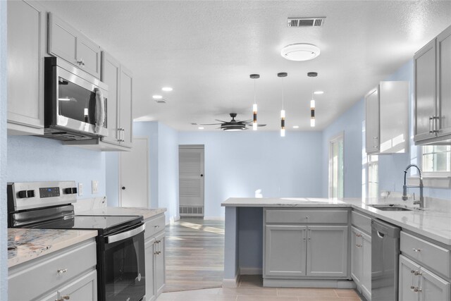 kitchen with gray cabinetry, sink, ceiling fan, appliances with stainless steel finishes, and kitchen peninsula