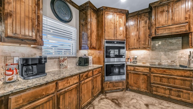 kitchen featuring black stovetop, backsplash, light stone counters, and stainless steel double oven