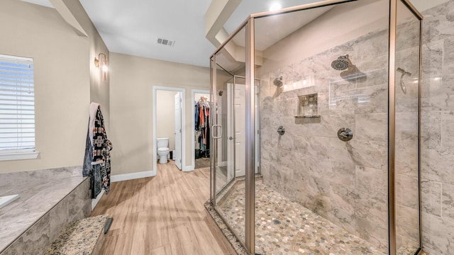 bathroom with toilet, hardwood / wood-style floors, and walk in shower