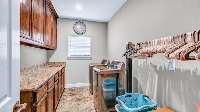 clothes washing area with cabinets, washer and dryer, and sink