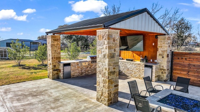 view of patio with area for grilling, a gazebo, an outdoor fire pit, and exterior kitchen