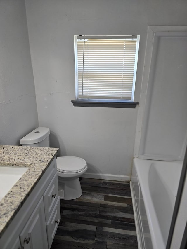 bathroom with hardwood / wood-style flooring, vanity, a bathtub, and toilet