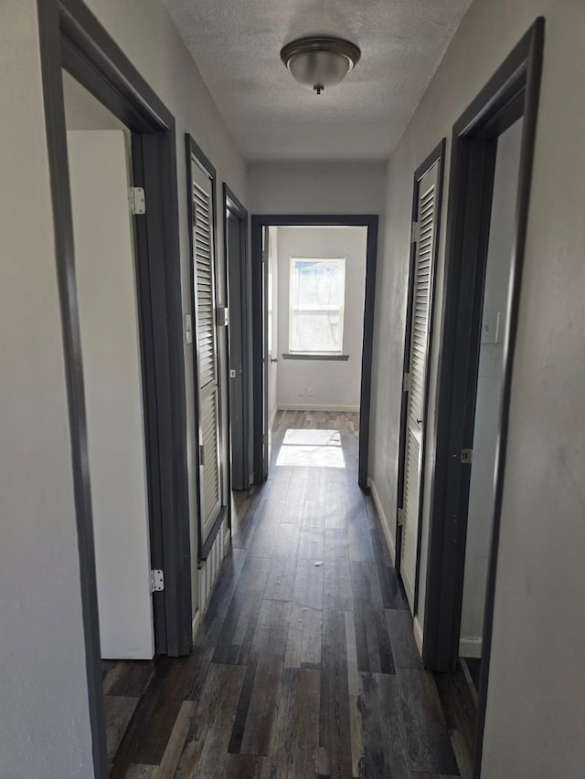 hallway with dark hardwood / wood-style flooring and a textured ceiling