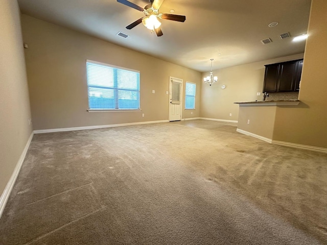 unfurnished living room featuring ceiling fan with notable chandelier and dark colored carpet