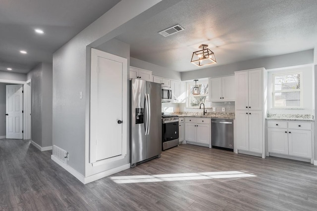 kitchen with stainless steel appliances, white cabinetry, tasteful backsplash, and dark wood-type flooring