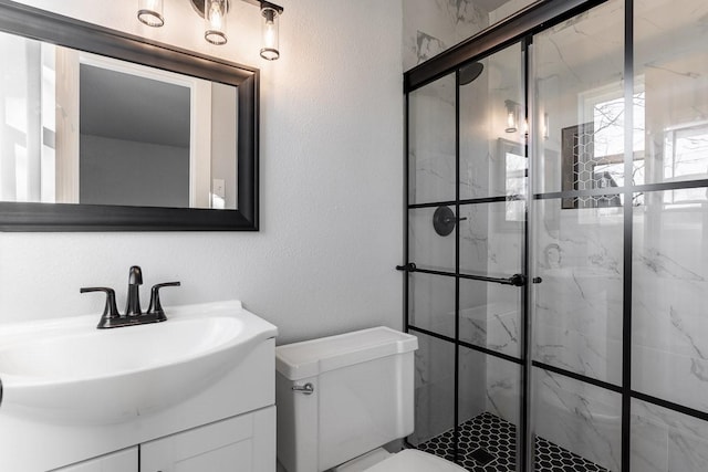 bathroom with a shower with door, vanity, and toilet