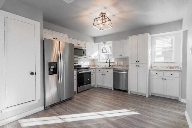 kitchen with sink, white cabinetry, stainless steel appliances, and light wood-type flooring