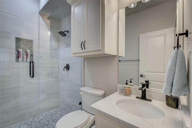 bathroom featuring vanity, toilet, and a shower with door