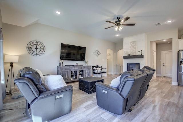 living room with ceiling fan, a fireplace, and light wood-type flooring