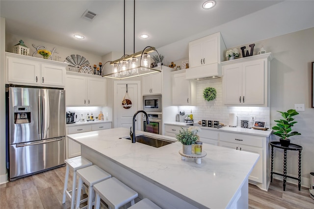 kitchen featuring white cabinetry, a center island with sink, and stainless steel appliances