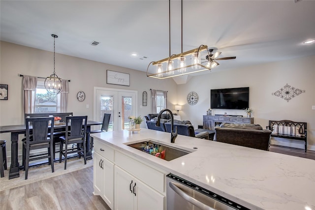 kitchen featuring pendant lighting, french doors, sink, light stone counters, and white cabinetry