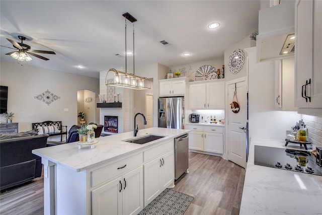 kitchen with a kitchen island with sink, sink, white cabinets, and appliances with stainless steel finishes