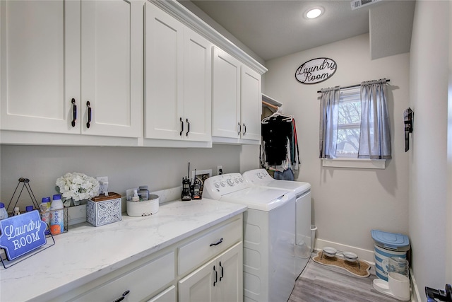 laundry room with washing machine and dryer, cabinets, and light wood-type flooring