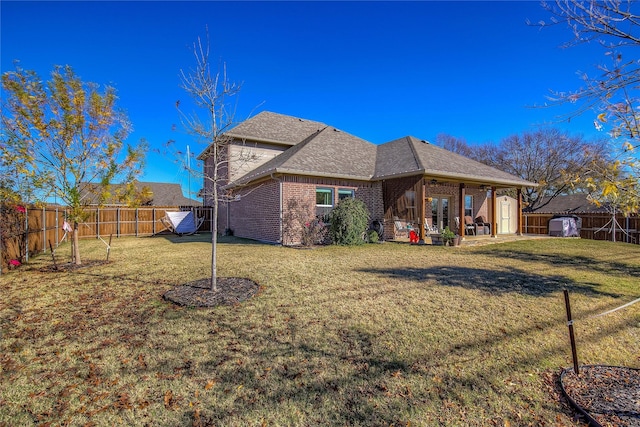 rear view of property with a storage shed, a yard, and a patio