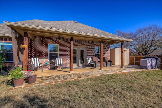 back of house with a storage shed, a yard, and a patio