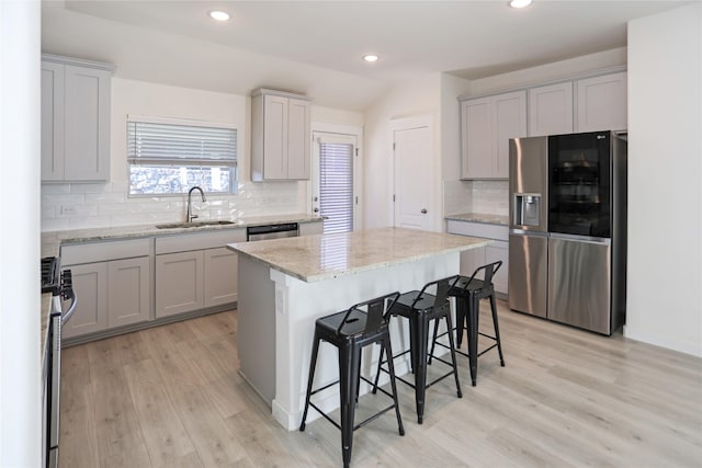 kitchen with sink, gray cabinets, stainless steel appliances, and a kitchen island