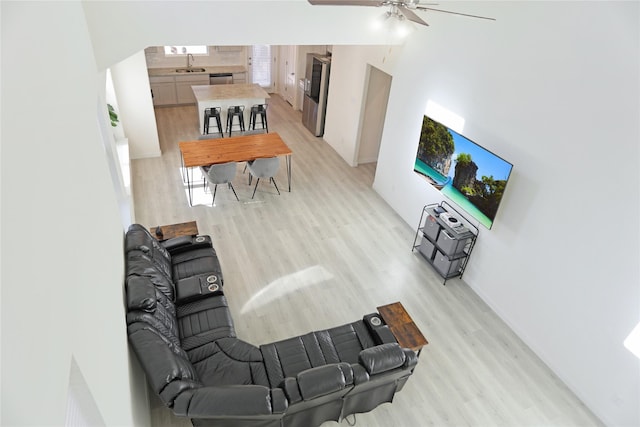 living room featuring ceiling fan, sink, and light hardwood / wood-style floors