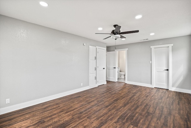 unfurnished bedroom with ceiling fan, dark wood-type flooring, and ensuite bath