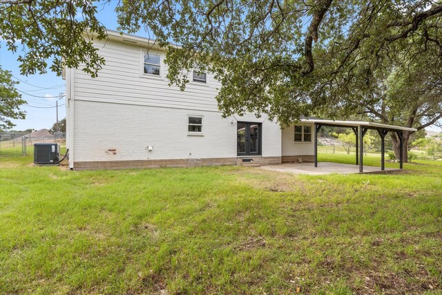 back of property with a lawn and central AC