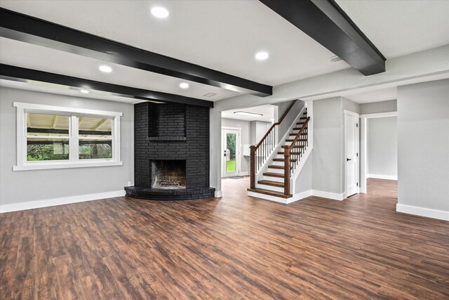 unfurnished living room with beam ceiling, dark hardwood / wood-style flooring, and a brick fireplace