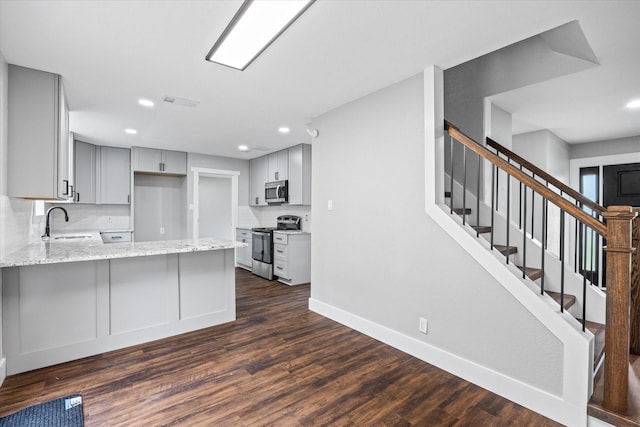 kitchen featuring appliances with stainless steel finishes, tasteful backsplash, gray cabinetry, dark wood-type flooring, and sink