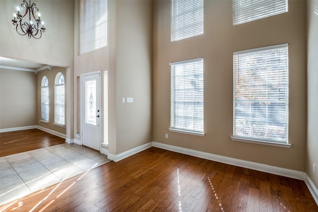 foyer entrance featuring light hardwood / wood-style floors, a towering ceiling, and a chandelier