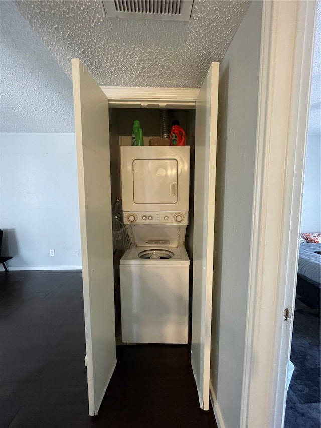 laundry area featuring stacked washing maching and dryer and a textured ceiling