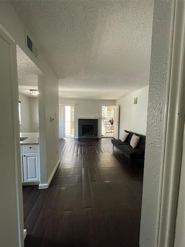 hall featuring a textured ceiling and dark wood-type flooring