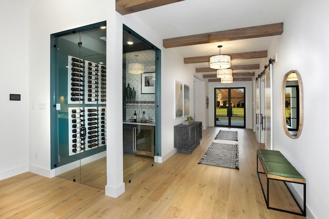 interior space featuring a barn door, beamed ceiling, and light wood-type flooring